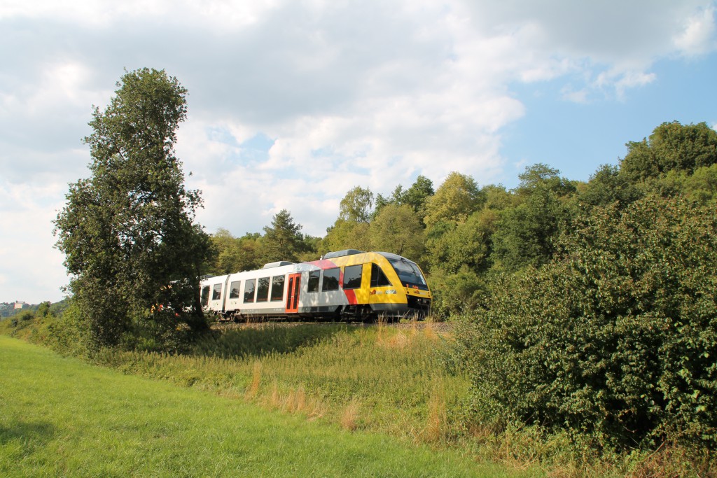 Aus dem Gebüsch zwischen Runkel und Villmar auf der Lahntalbahn schaut am 01.08.2015 ein LINT der HLB hervor.