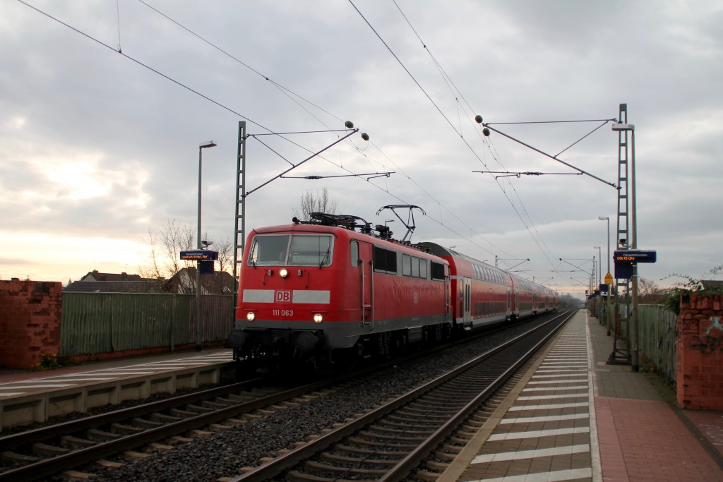 111 063 legt mit ihrem Zug aus Doppelstockwagen einen kurzen Halt in Bürstadt auf der Reitbahn ein, aufgenommen am 21.11.2015.