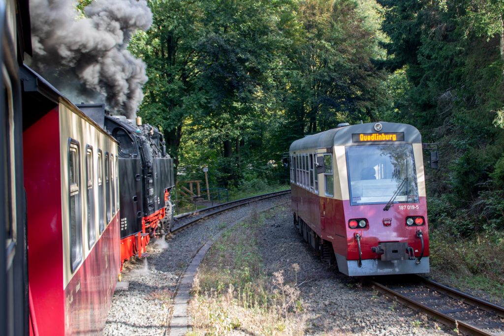 Gemeinsame Ausfahrt von 99 7235 und 187 019 aus dem Bahnhof Eisfelder-Talmühle auf der Harzquerbahn, aufgenommen am 02.10.2023.