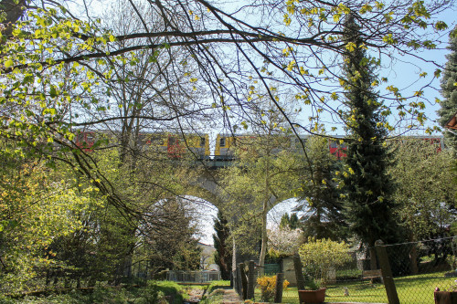 Zwei VT2E der HLB überqueren hinter den Bäumen das Viadukt in Neu-Anspach auf der Taunusbahn, aufgenommen am 23.04.2015.