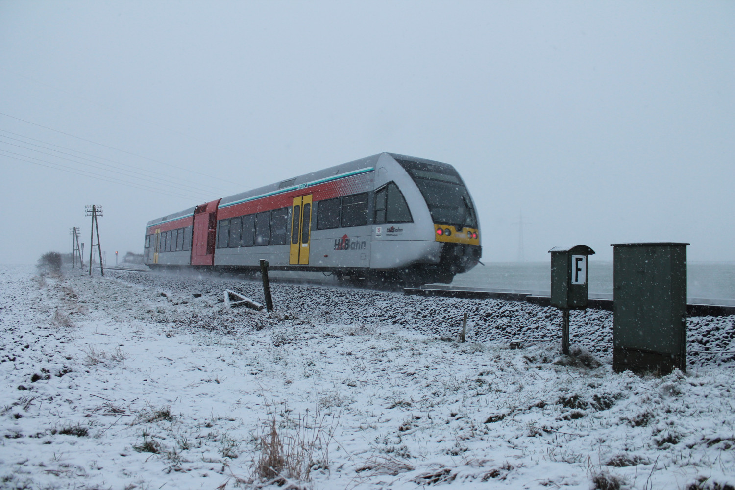 Im Schneetreiben am 24.01.2015 passiert ein GTW 2/6 der HLB den ehemaligen Bahnübergang zwischen Lich und Langsdorf auf der Lahn-Kinzig-Bahn.