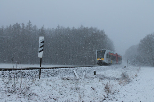 Im Schneetreiben am 24.01.2015 passiert ein GTW 2/6 der HLB den ehemaligen Bahnübergang zwischen Lich und Langsdorf auf der Lahn-Kinzig-Bahn.